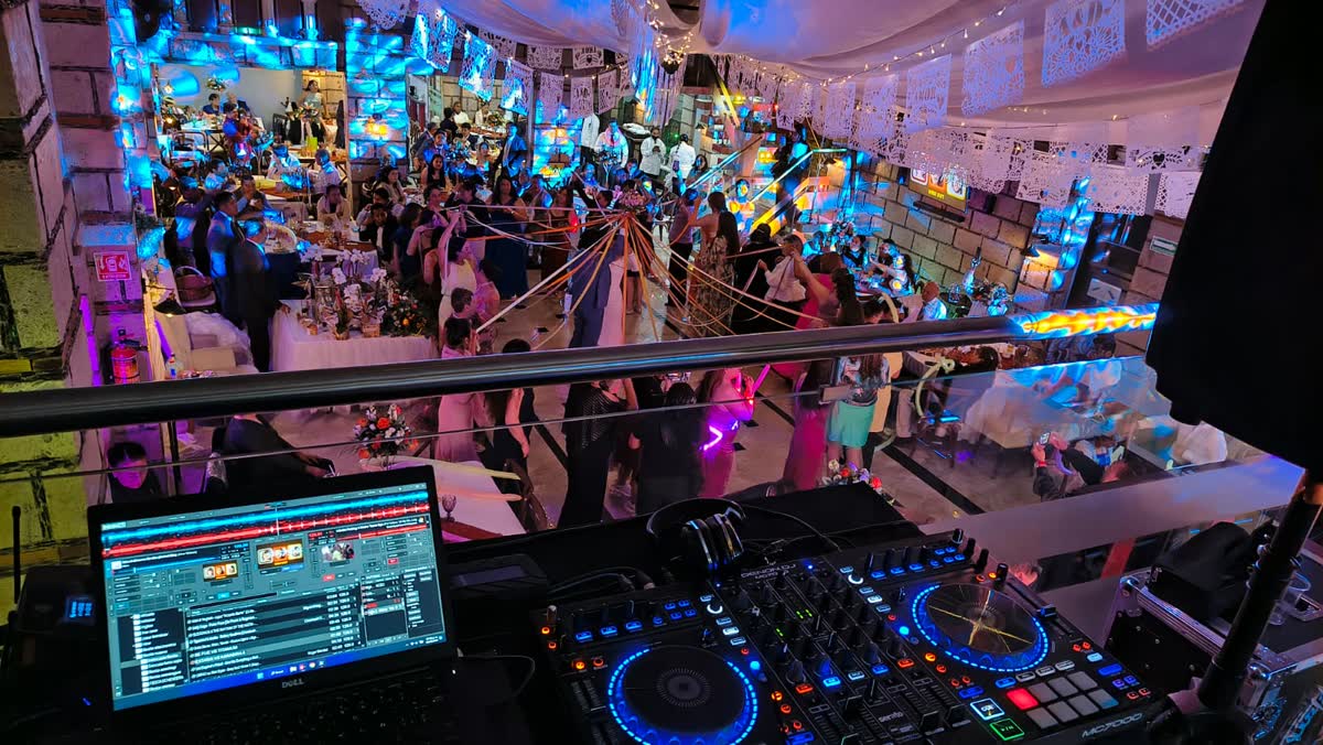 Pista de baile llena durante una boda en la Ciudad de México, con papel picado y luces de color