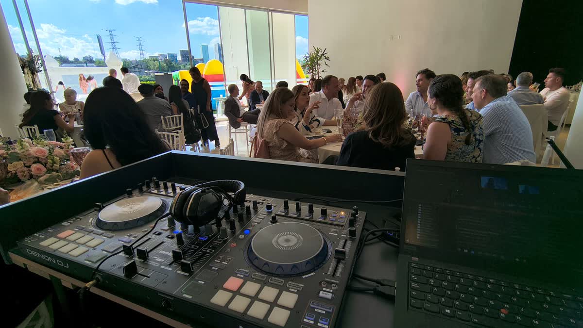 Boda de día en terraza con vista a la ciudad, mesas decoradas y cabina de DJ