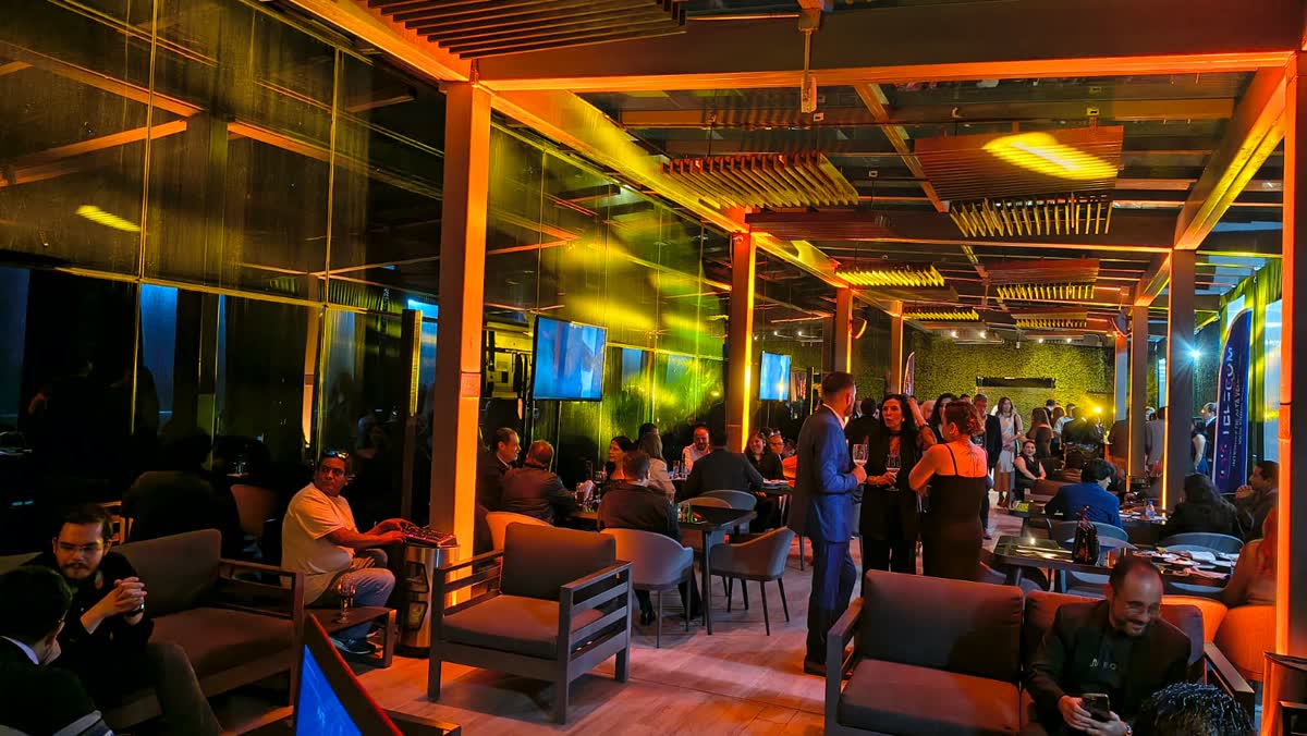Cóctel corporativo con iluminación ambiental ámbar y pantallas